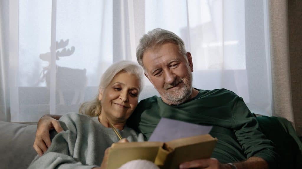 A mature couple reading a book together.
