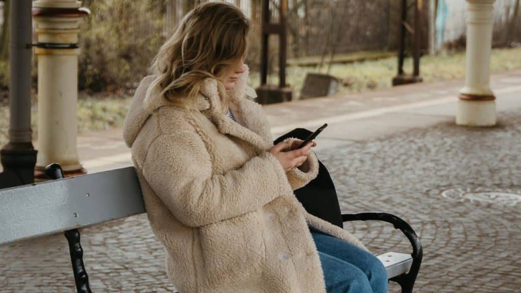 A person sitting on a bench and looking at a phone.