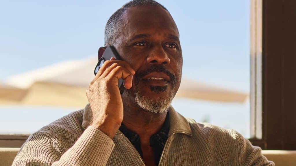 A man talking on a phone near a window.