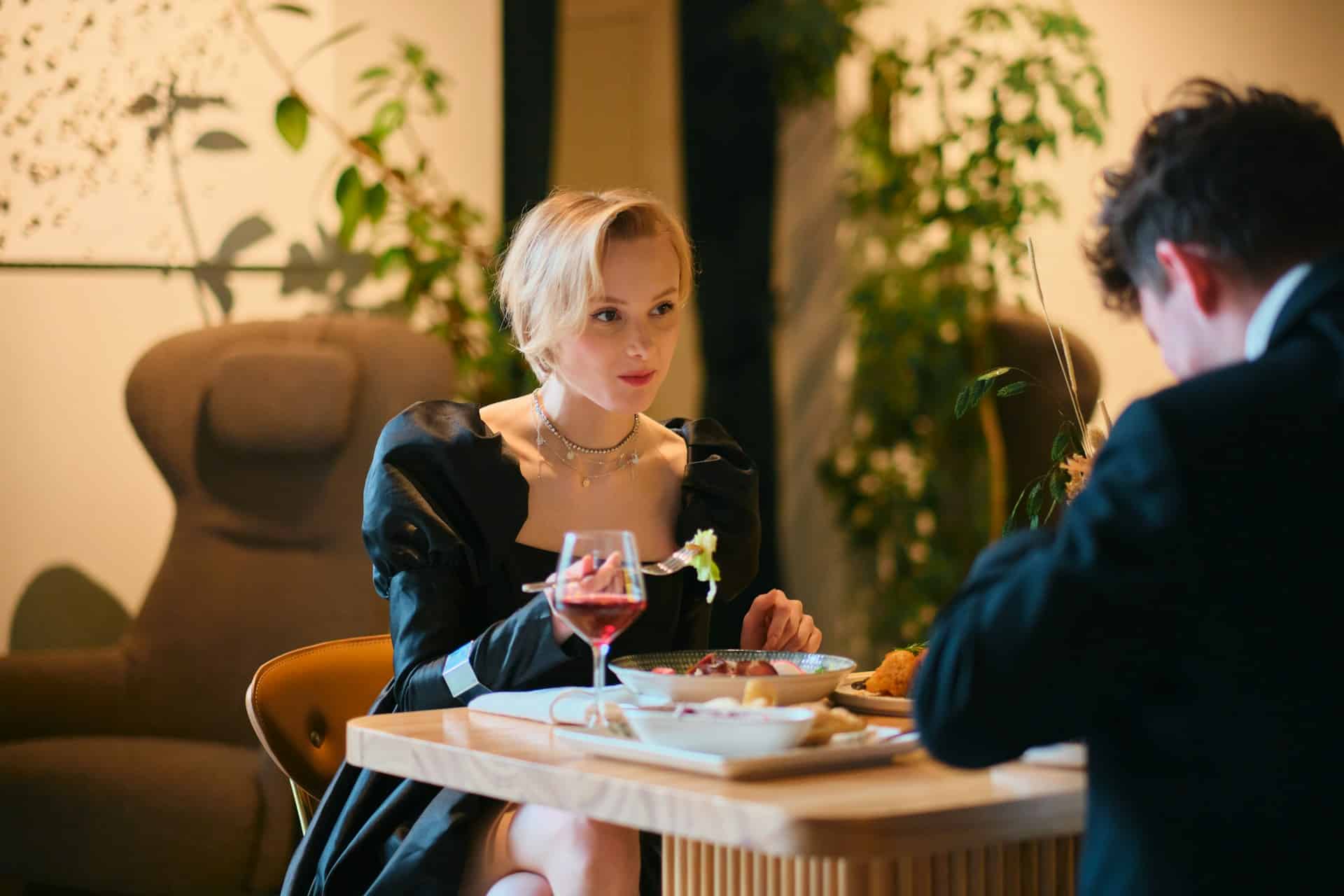 A woman sitting across from the man at a fancy restaurant.