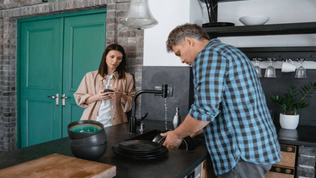 A woman watching her husband do the dishes 
