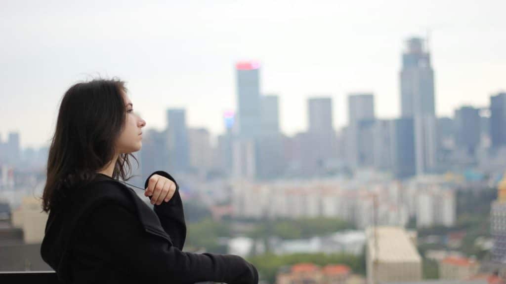 A person in profile looking out over a distant city skyline.