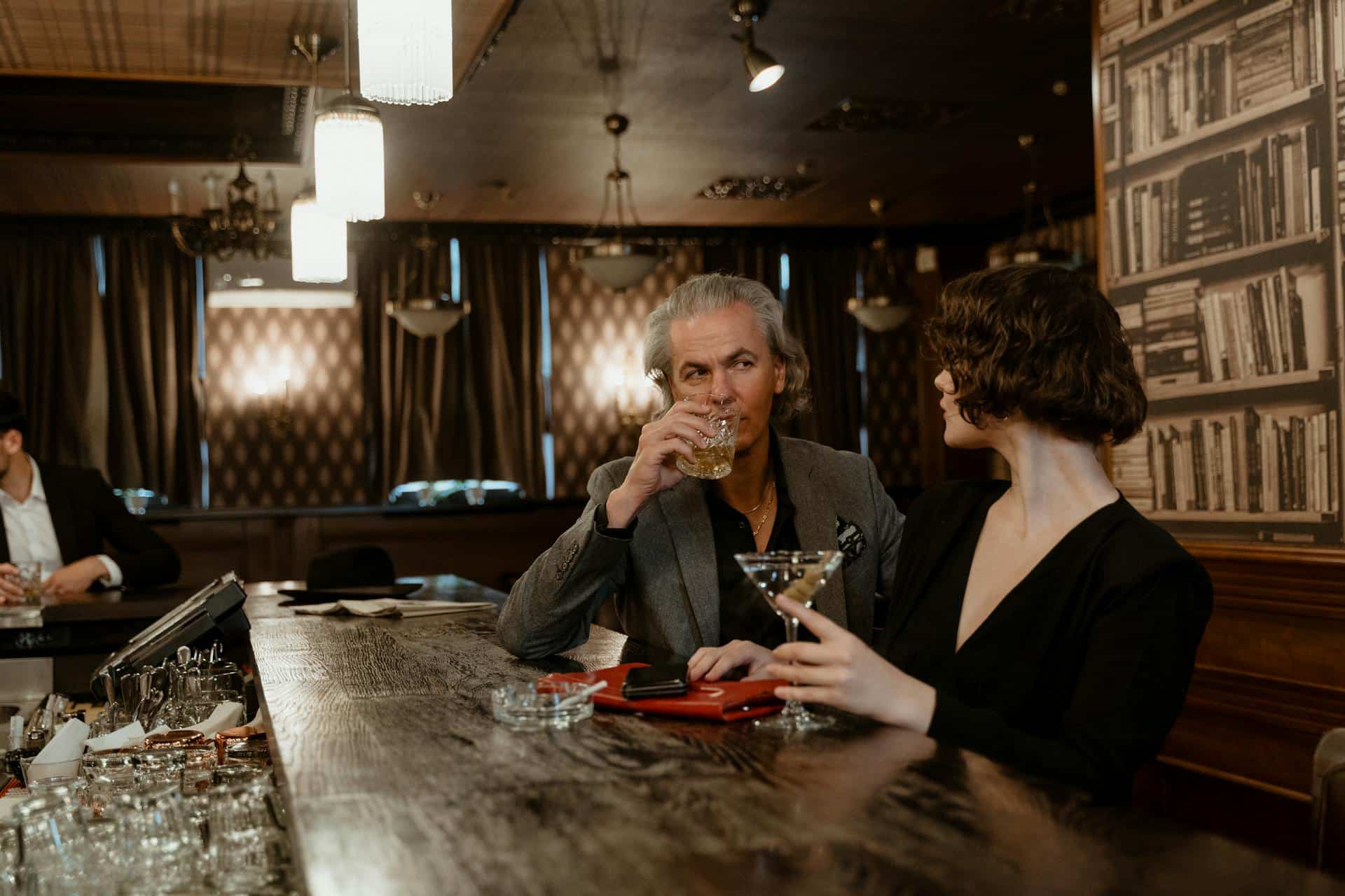 A mature man having drinks with a woman at the bar