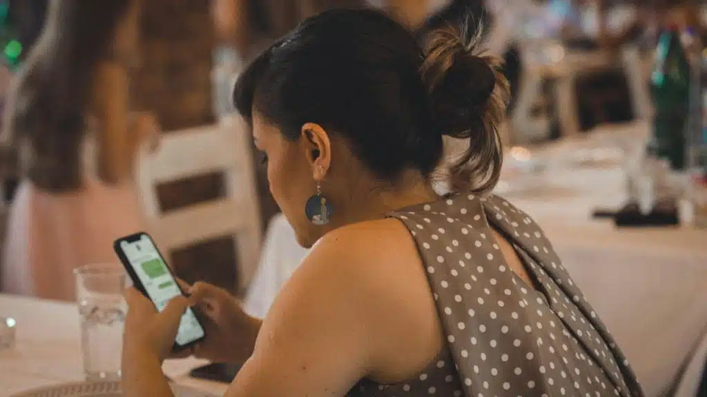 A woman using a cellphone while sitting at a table.