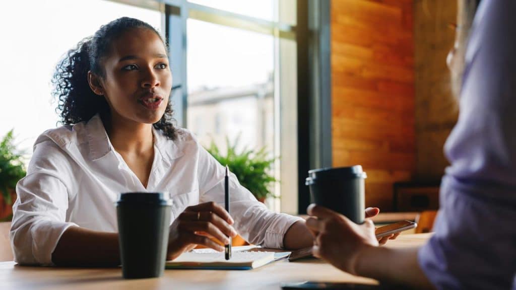 A woman talking during a coffee meeting at a café table.