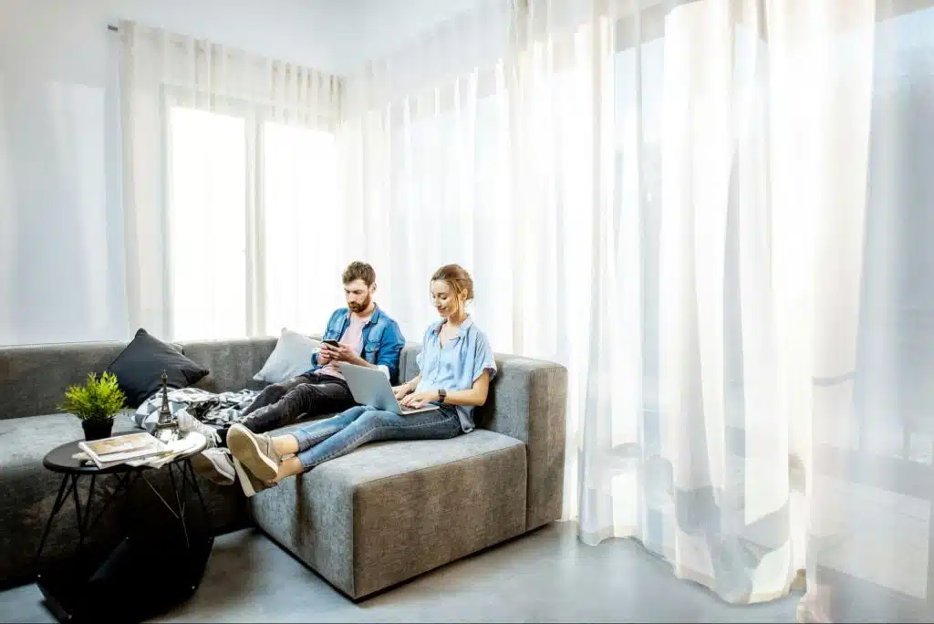 A couple at the living room scrolling through their mobile phones
