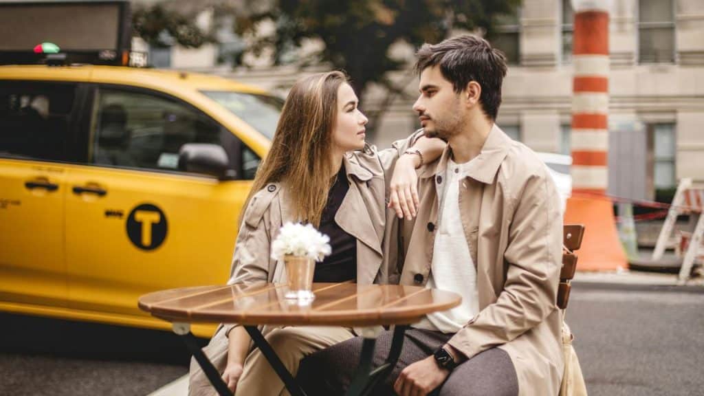 A couple sitting closely at a small outdoor café table on a city street.