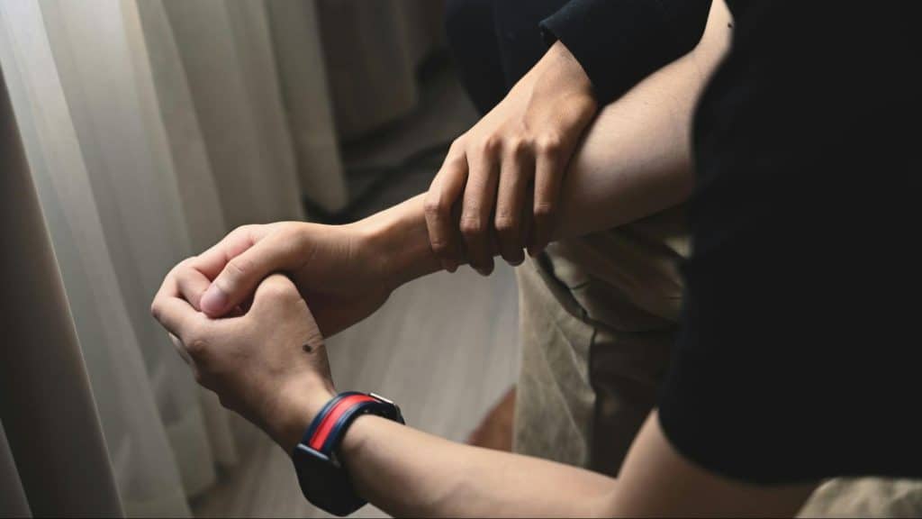 A woman holding her husband’s wrist for support