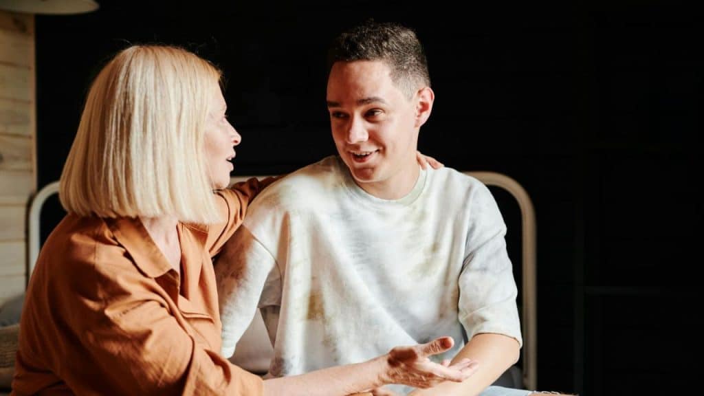 A man smiles and gestures with his hand while a woman looks at him.