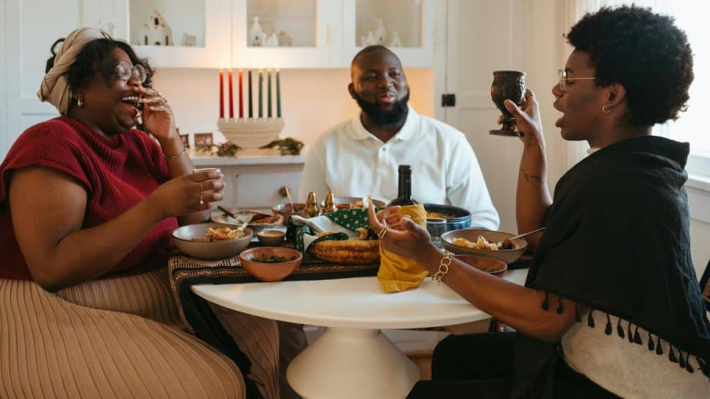 A group of friends laughing and sharing a meal around a dining table.