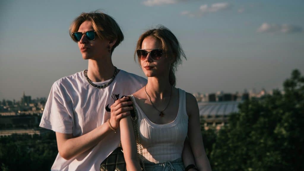 A couple wearing glasses standing outdoors.