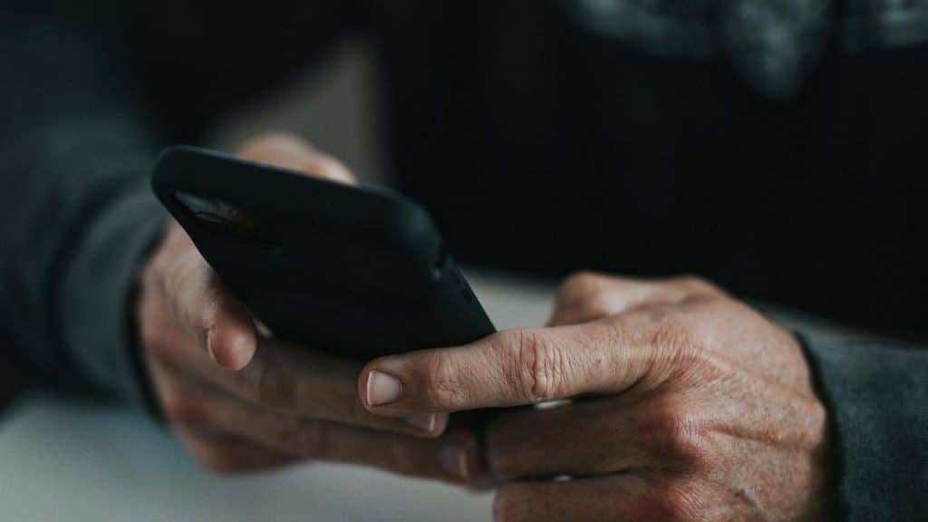A close-up of hands holding and using a smartphone.