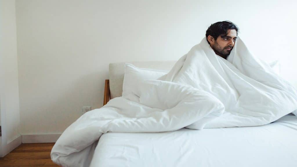 A man wrapped in a blanket looking sad