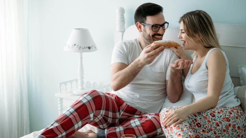 A young, attractive, loving couple in a bedroom.