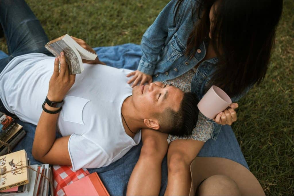 A man smiling while lying on woman’s legs 