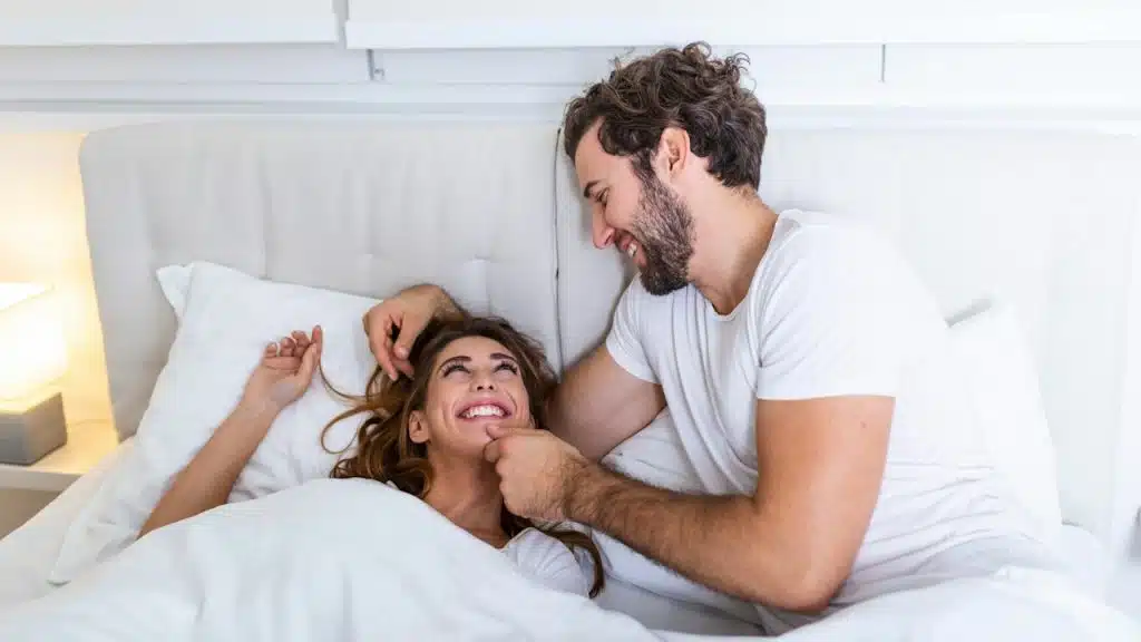Happy couple is lying in bed together, enjoying the company of each other.