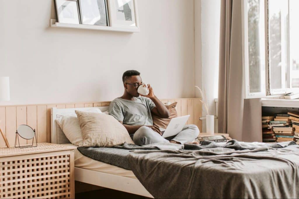 A man at the bed using a laptop 
