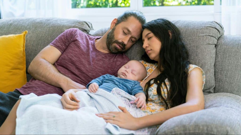 A man and woman sleeping with their baby