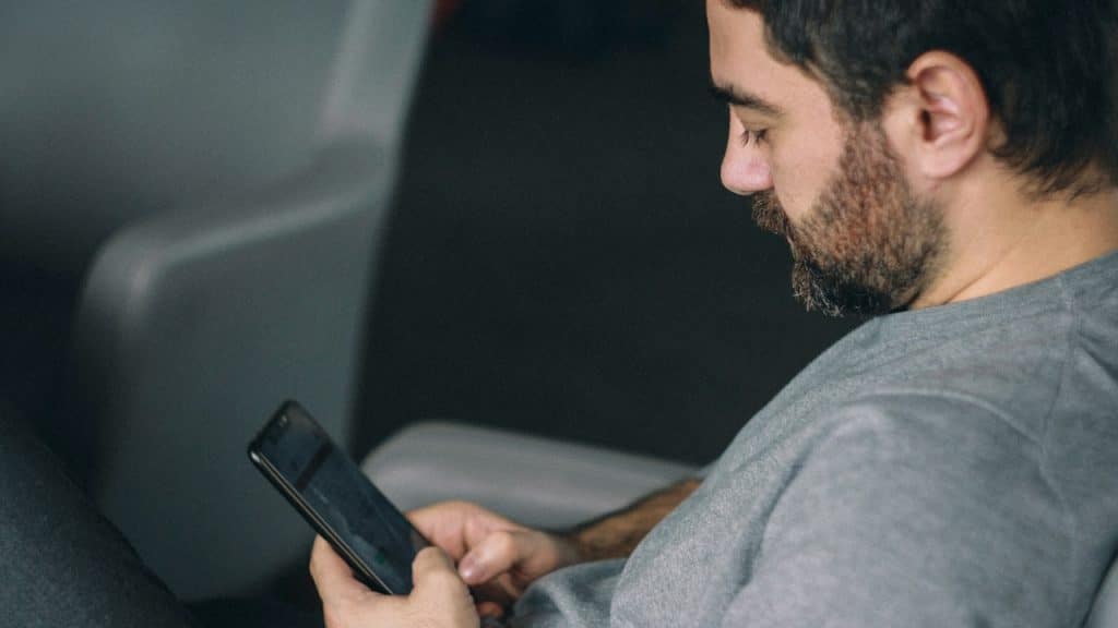 A bearded man using his phone.