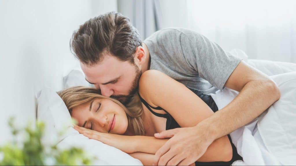 A man kissing a woman while sleeping