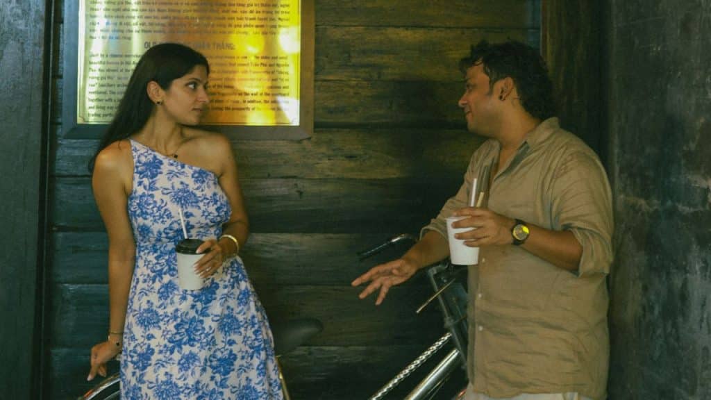 A man and a woman stand near a bicycle while holding white disposable cups.