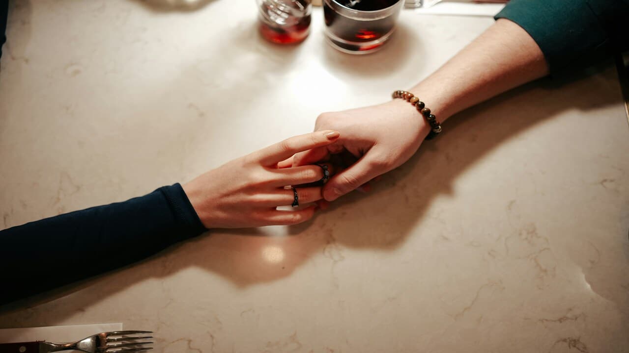 A couple holding hands over the table