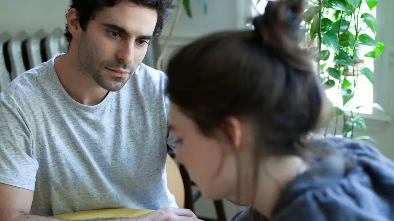 A man in a grey shirt looks intently at a woman from a side view.