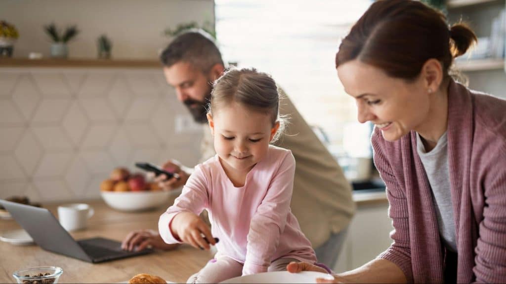 A man making himself busy with work and a woman taking care of a child