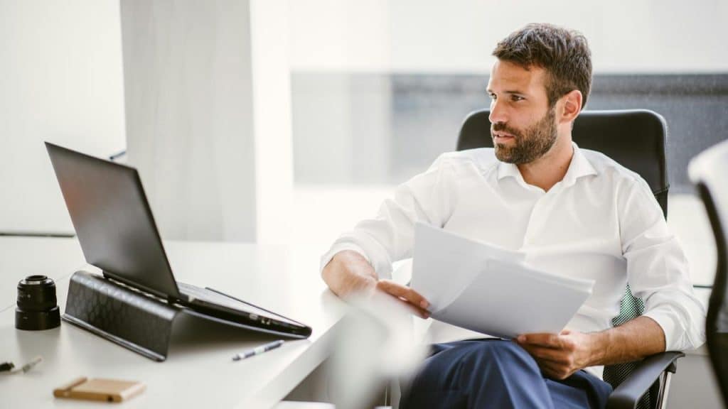 A man working at a desk with a laptop and papers.