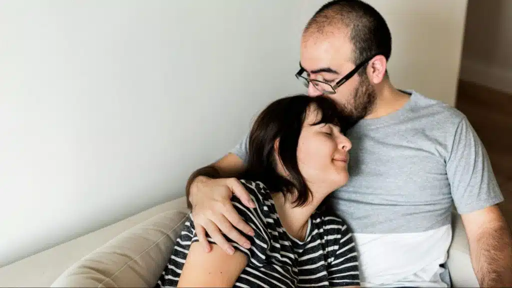 A man kissing woman’s head