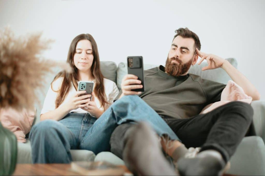 A man and woman busy scrolling through their phones