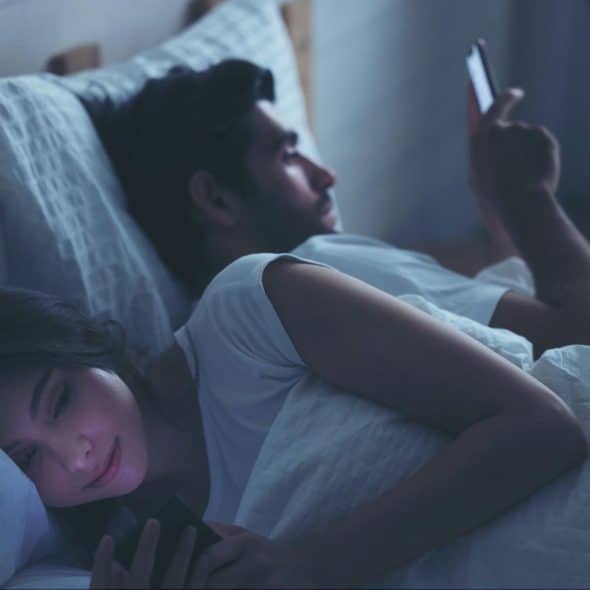 A man and woman busy using a phone