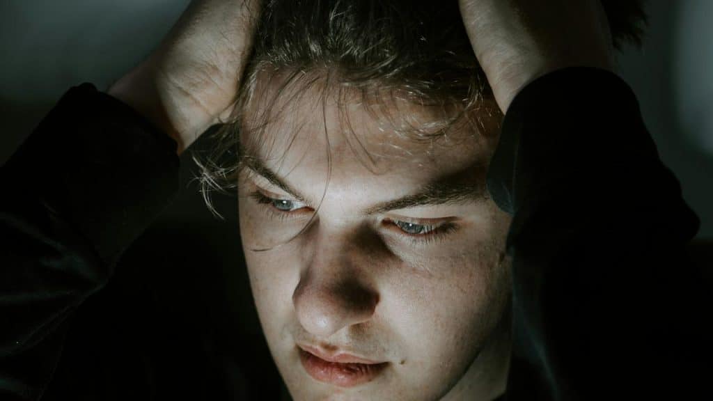 A person holding their head with both hands, looking stressed or deep in thought.