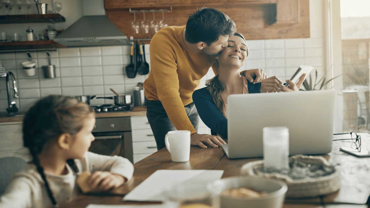 A man giving his wife a kiss during breakfast