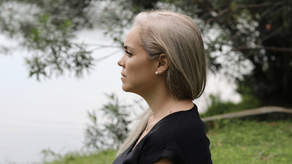 A woman looking upset by a body of water