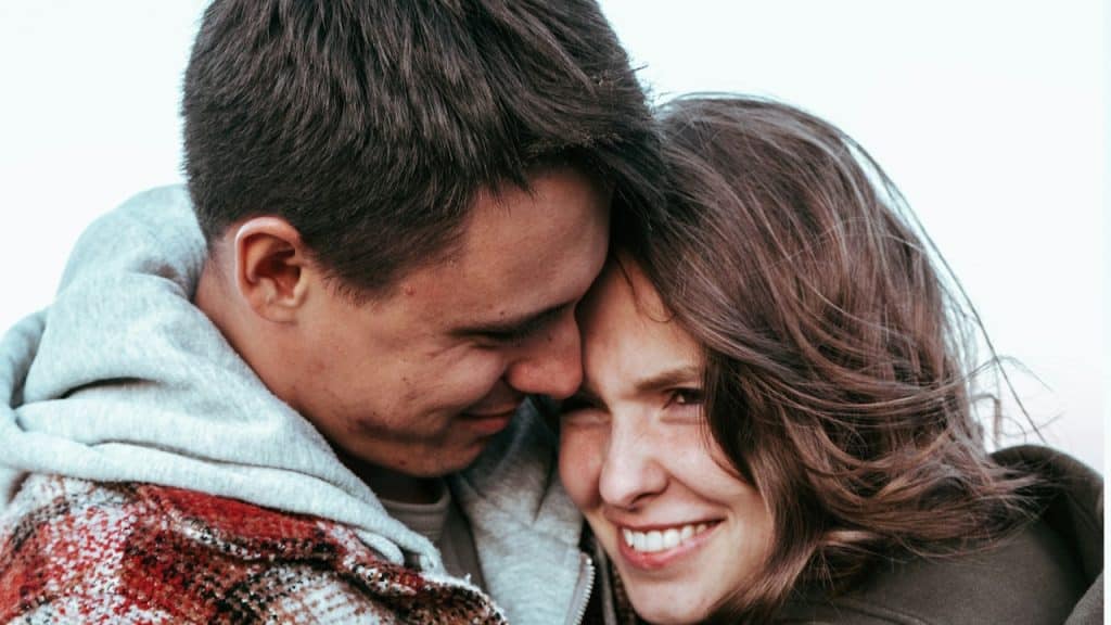 A couple snuggling and smiling.