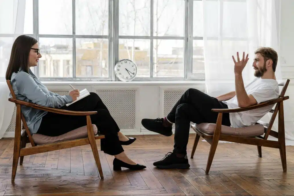 A man and woman talking while sitting at the chair