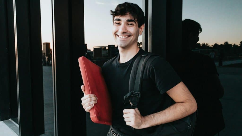 A man holding a red object in front of a window.