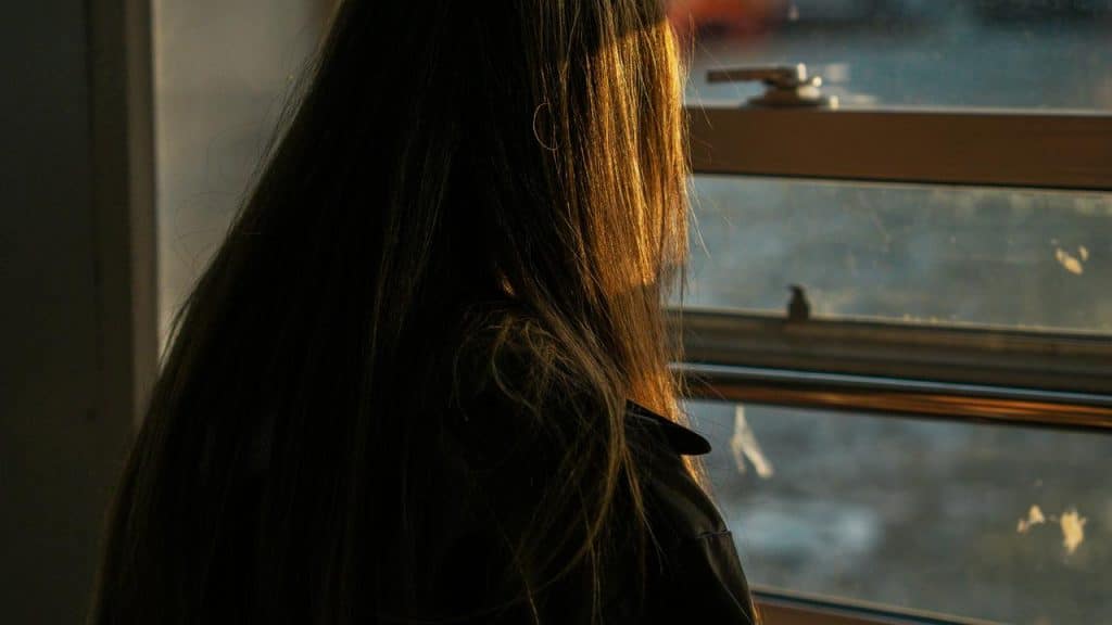 A person standing by a window with sunlight on their hair.