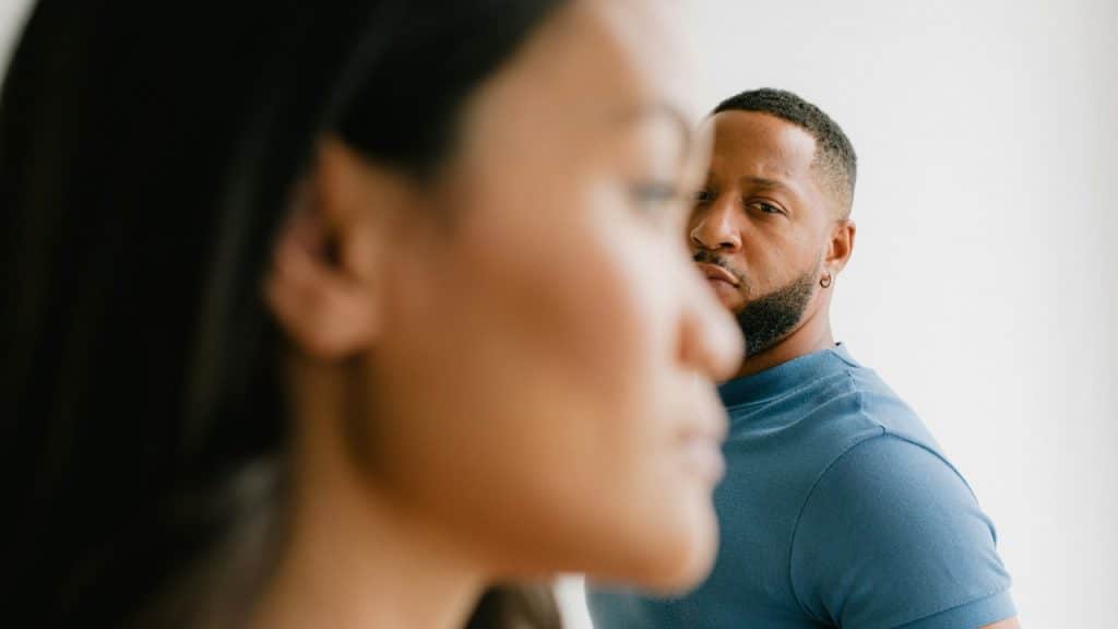 A man with a beard looks intensely at the side of a woman’s blurred face.