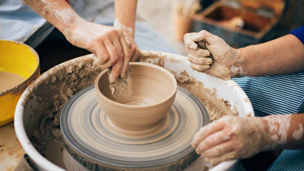 A potter shaping a clay bowl on a spinning wheel.