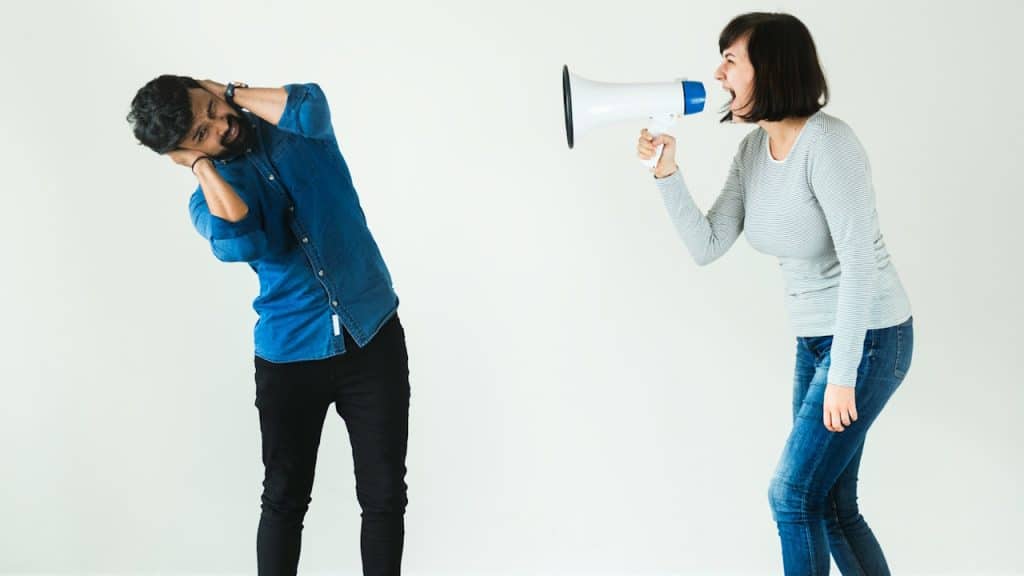 A woman shouting to a man by megaphone.