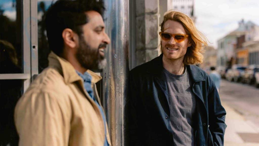A pair of men chatting casually on a city street in daylight.
