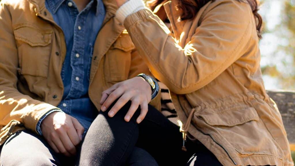 A couple sitting close together, touching each other’s hands and faces.