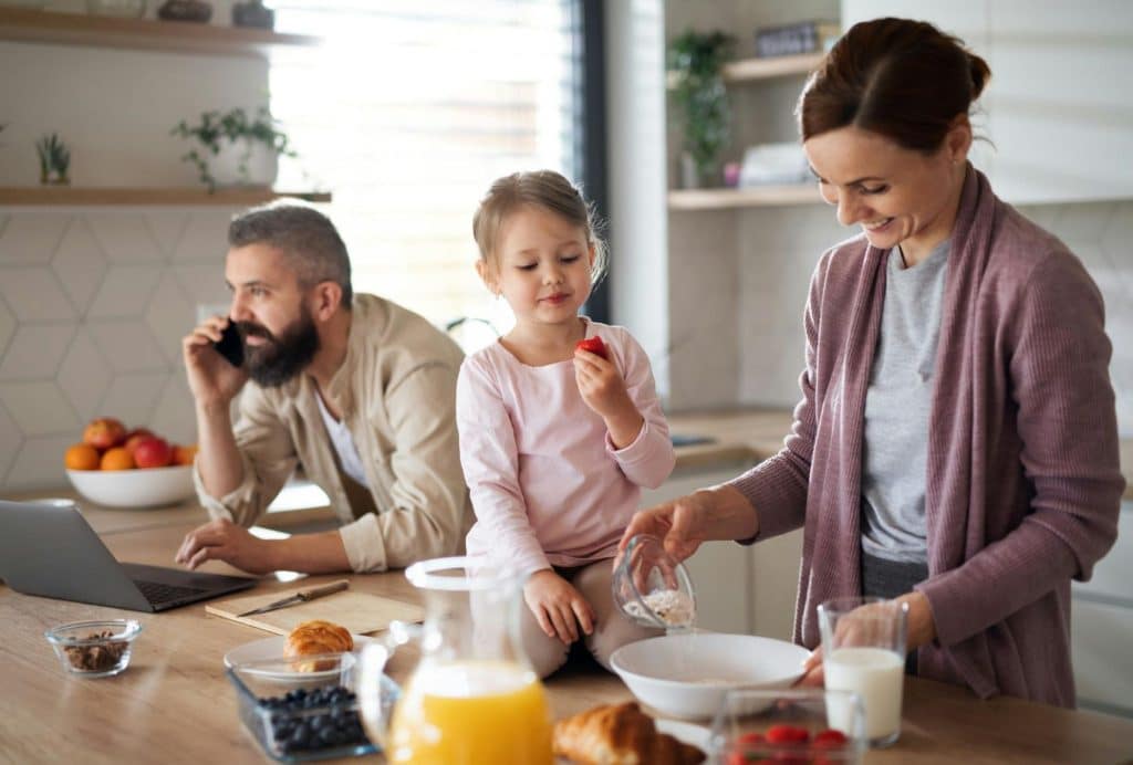 A man busy working and a woman entertaining their daughter