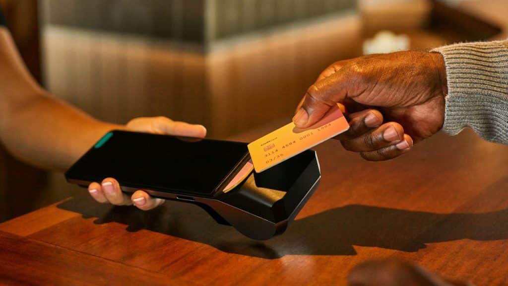 A man using his debit card to pay for something while tapping it on a cash machine.