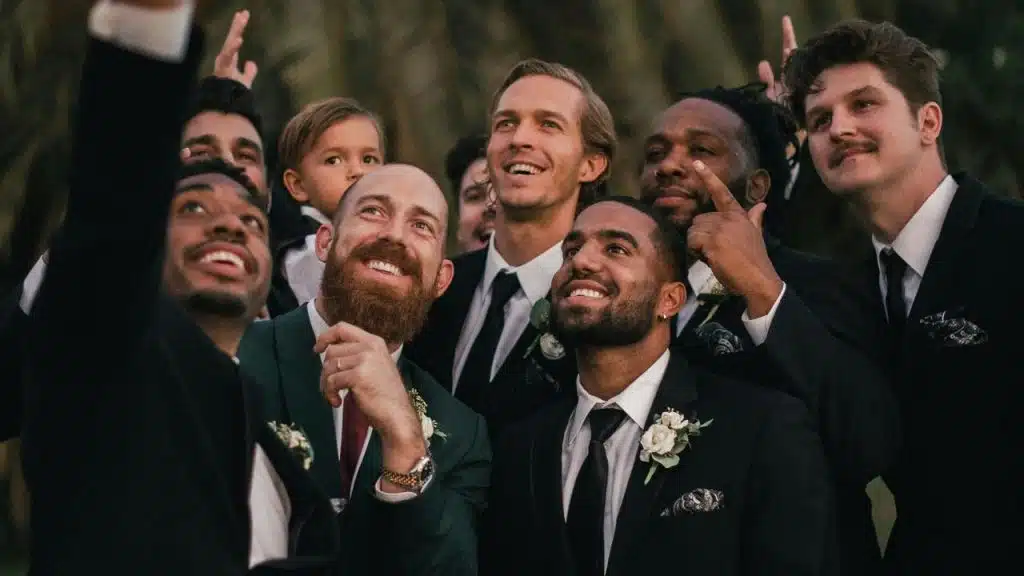 A joyful group of men in suits smiling together at an outdoor wedding.He had a whole existence before he met you. Friends who knew him in college, hobbies that shaped who he became, memories that still make him smile. When you act like none of that matters, like his life really started the day you walked into it, you erase a huge part of who he actually became. And trust me, he notices.