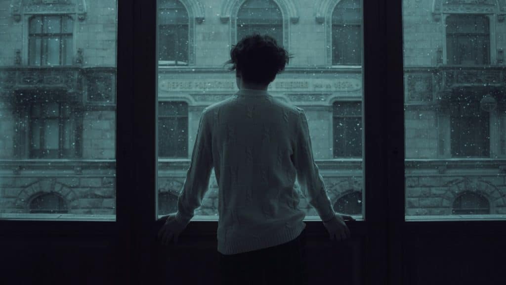 A woman in a white shirt standing in front of a window.
