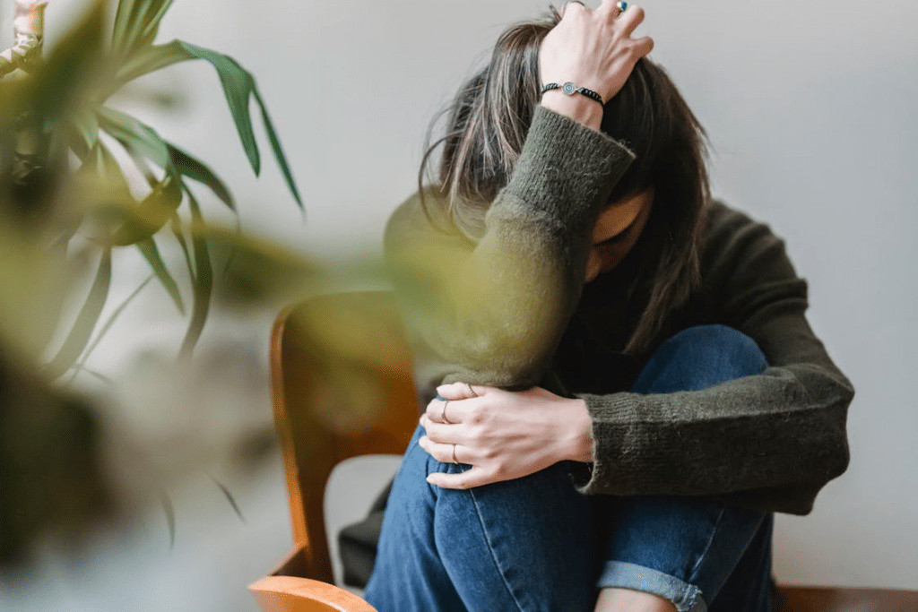 Upset lady embracing knees sitting on chair