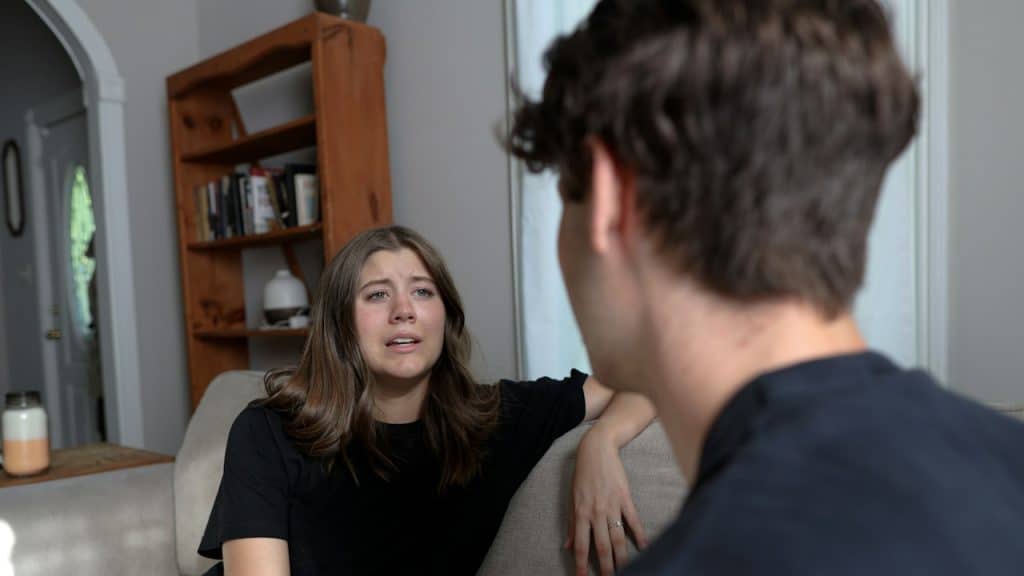 A woman sitting on a couch talking to a man.
